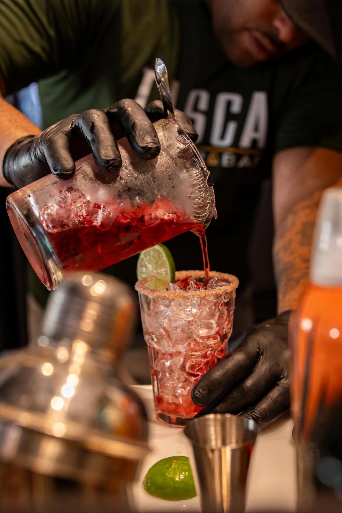 Bartender pouring a cocktail into a glass